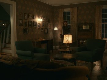 Movie still from “I'm Thinking of Ending Things” (2020), directed by Charlie Kaufman – A woman standing in a living room with a lamp; Wide shot, High angle