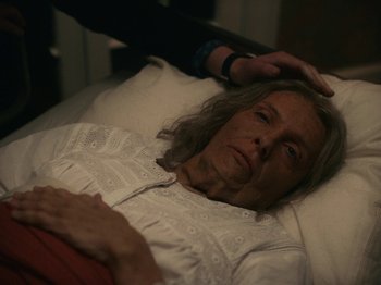 Movie still from “I'm Thinking of Ending Things” (2020), directed by Charlie Kaufman – An older woman laying in a bed with an older woman touching her hair; Close Up shot, High angle