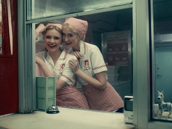 Movie still from “I'm Thinking of Ending Things” (2020), directed by Charlie Kaufman – Two women dressed in red and checkered aprons are posing for a picture; Medium shot, Overhead angle
