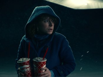 Movie still from “I'm Thinking of Ending Things” (2020), directed by Charlie Kaufman – A woman in a blue jacket holding two drinks; Medium shot, Low angle