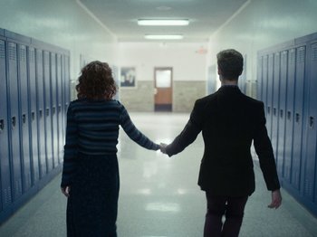 Movie still from “I'm Thinking of Ending Things” (2020), directed by Charlie Kaufman – A man and a woman holding hands while walking down a hall way; Medium shot, Low angle