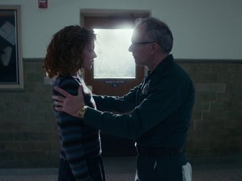 Movie still from “I'm Thinking of Ending Things” (2020), directed by Charlie Kaufman – An older man and a younger woman embracing in front of a window; Medium shot, Over the shoulder angle