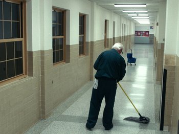 Movie still from “I'm Thinking of Ending Things” (2020), directed by Charlie Kaufman – An older man sweeping the floor in a hallway; Wide shot, High angle