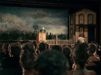 Movie still from “I'm Thinking of Ending Things” (2020), directed by Charlie Kaufman – A crowd of people watching a man on a stage; Wide shot, Over the shoulder angle