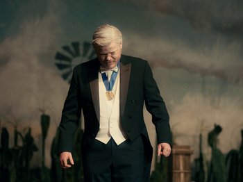 Movie still from “I'm Thinking of Ending Things” (2020), directed by Charlie Kaufman – An older man in a tuxedo with a medal around his neck; Medium shot, High angle