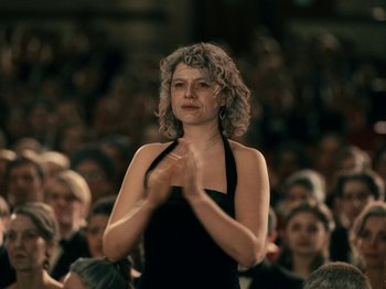 Movie still from “I'm Thinking of Ending Things” (2020), directed by Charlie Kaufman – A woman claps her hands in front of an audience; Medium shot, Low angle