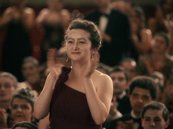 Movie still from “I'm Thinking of Ending Things” (2020), directed by Charlie Kaufman – A woman in a red dress clapping in front of an audience; Close Up shot, Over the shoulder angle