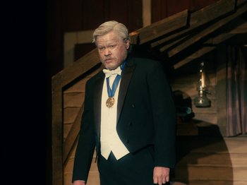 Movie still from “I'm Thinking of Ending Things” (2020), directed by Charlie Kaufman – An older man wearing a suit and a medal; Medium shot, High angle