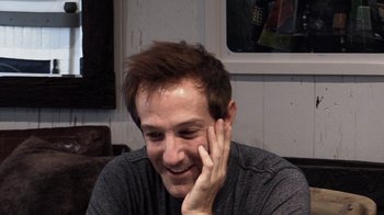 Movie still from “Icarus” (2017), directed by Bryan Fogel – A man smiling and holding his hand up to his face; Close Up shot, High angle