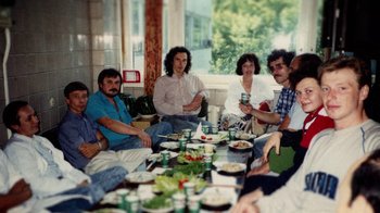 Movie still from “Icarus” (2017), directed by Bryan Fogel – A group of people sitting around a table with food on top of it; Medium shot, High angle