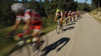 Movie still from “Icarus” (2017), directed by Bryan Fogel – A group of people riding bikes down a street; Extreme Wide shot, High angle