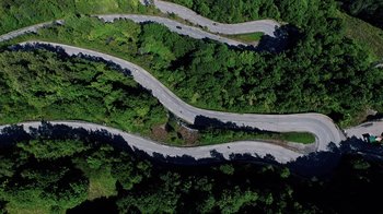 Movie still from “Icarus” (2017), directed by Bryan Fogel – An aerial view of a winding road through the trees; Extreme Wide shot, Overhead angle