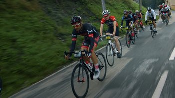 Movie still from “Icarus” (2017), directed by Bryan Fogel – A group of men riding bikes down a street; Wide shot, High angle