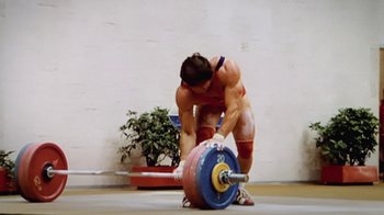 Movie still from “Icarus” (2017), directed by Bryan Fogel – A man is lifting a barbell in a gym; Medium shot, Low angle