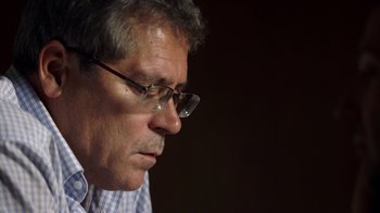 Movie still from “Icarus” (2017), directed by Bryan Fogel – An older man wearing glasses looking down at something; Close Up shot, Low angle