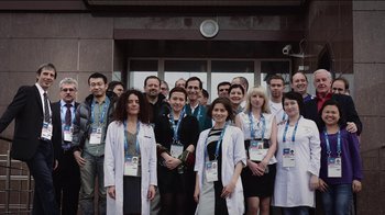 Movie still from “Icarus” (2017), directed by Bryan Fogel – A group of people standing next to each other wearing white lab coats; Wide shot, Low angle