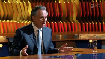 Movie still from “Icarus” (2017), directed by Bryan Fogel – A man wearing a suit and tie sitting at a table; Medium shot, Low angle