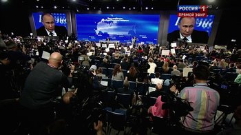 Movie still from “Icarus” (2017), directed by Bryan Fogel – A crowd of people sitting in chairs in front of a large screen; Extreme Wide shot, Over the shoulder angle
