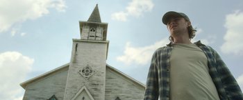Movie still from “In the Tall Grass” (2019), directed by Vincenzo Natali – A man standing in front of an old church; Medium shot, Low angle