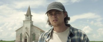 Movie still from “In the Tall Grass” (2019), directed by Vincenzo Natali – A man wearing a hat and a plaid shirt; Close Up shot, Low angle