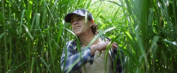 Movie still from “In the Tall Grass” (2019), directed by Vincenzo Natali – A young man in a field of tall green grass; Medium shot, Low angle
