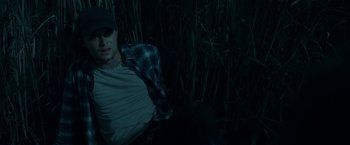 Movie still from “In the Tall Grass” (2019), directed by Vincenzo Natali – A man sitting in the grass at night; Medium shot, High angle