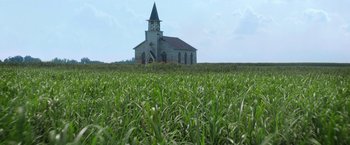 Movie still from “In the Tall Grass” (2019), directed by Vincenzo Natali – An old church sits in the middle of a field of grass; Extreme Wide shot, Low angle