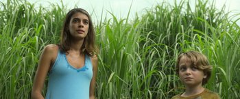 Movie still from “In the Tall Grass” (2019), directed by Vincenzo Natali – A woman standing in a field of tall green grass; Close Up shot, Low angle