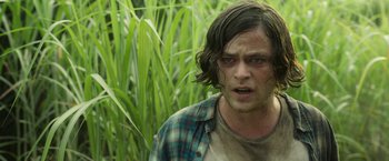 Movie still from “In the Tall Grass” (2019), directed by Vincenzo Natali – A man in a plaid shirt is standing in the grass; Close Up shot, Over the shoulder angle