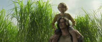 Movie still from “In the Tall Grass” (2019), directed by Vincenzo Natali – A man and a boy are standing in a field; Medium shot, Low angle