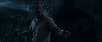 Movie still from “In the Tall Grass” (2019), directed by Vincenzo Natali – A man is holding his hands out in the dark; Medium shot, Low angle