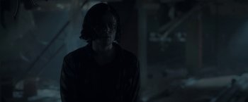 Movie still from “In the Tall Grass” (2019), directed by Vincenzo Natali – A man standing in a dark room looking at the camera; Close Up shot, Over the shoulder angle