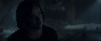 Movie still from “In the Tall Grass” (2019), directed by Vincenzo Natali – A man with long black hair is looking at the camera; Close Up shot, Over the shoulder angle