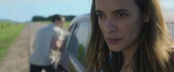 Movie still from “In the Tall Grass” (2019), directed by Vincenzo Natali – A person with a car in the background; Close Up shot, Over the shoulder angle