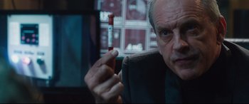 Movie still from “Incarnate” (2016), directed by Brad Peyton – An older man is pointing at something in his hand; Close Up shot, Over the shoulder angle