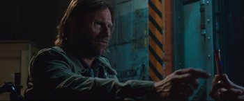 Movie still from “Incarnate” (2016), directed by Brad Peyton – A man sitting in front of a wall with his hand on the wall; Close Up shot, Low angle