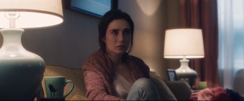 Movie still from “Incarnate” (2016), directed by Brad Peyton – A woman sitting on top of a couch in a living room; Close Up shot, Over the shoulder angle
