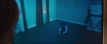 Movie still from “Incarnate” (2016), directed by Brad Peyton – A person sitting on the floor in a room; Wide shot, High angle