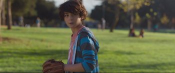 Movie still from “Incarnate” (2016), directed by Brad Peyton – A young boy holding a baseball glove on a field; Medium shot, Over the shoulder angle