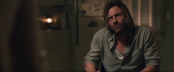 Movie still from “Incarnate” (2016), directed by Brad Peyton – A man sitting in a chair in a dark room; Medium shot, Over the shoulder angle