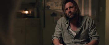 Movie still from “Incarnate” (2016), directed by Brad Peyton – A man sitting in a chair in a room; Medium shot, Over the shoulder angle