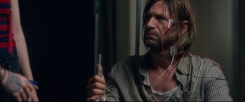Movie still from “Incarnate” (2016), directed by Brad Peyton – A man with headphones on holding an electronic device; Close Up shot, Over the shoulder angle