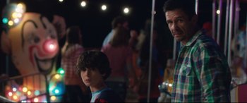 Movie still from “Incarnate” (2016), directed by Brad Peyton – A man and a boy standing next to each other in front of a crowd; Medium shot, Over the shoulder angle