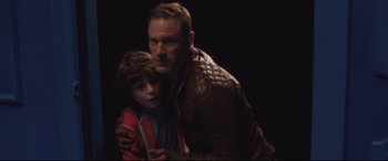 Movie still from “Incarnate” (2016), directed by Brad Peyton – A man and a boy are hugging in a dark room; Medium shot, High angle