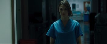 Movie still from “Incarnate” (2016), directed by Brad Peyton – A woman wearing a blue scrub top standing in a room; Close Up shot, Low angle
