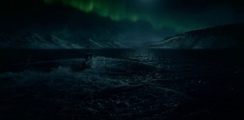 A boat in the ocean with a green light in the background
