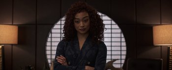 Movie still from “Kaleidoscope” (2023), directed by Mairzee Almas – A woman with curly red hair standing with her arms crossed; Close Up shot, Over the shoulder angle