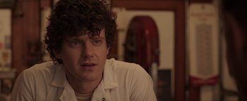 Movie still from “Kaleidoscope” (2023), directed by Mairzee Almas – A person with curly hair; Close Up shot, Over the shoulder angle