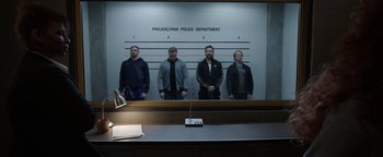 Movie still from “Kaleidoscope” (2023), directed by Mairzee Almas – A group of men standing in front of a police station; Wide shot, Low angle