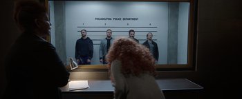 Movie still from “Kaleidoscope” (2023), directed by Mairzee Almas – A group of people standing in front of a police station; Wide shot, Low angle